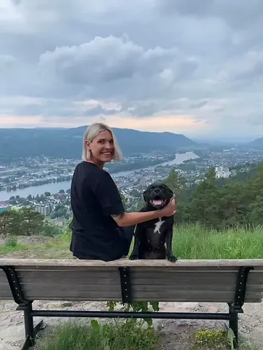 Photo of Dee sat on a bench with her dog.