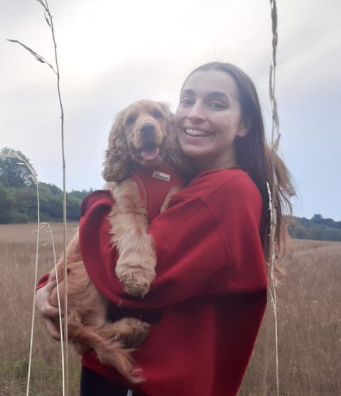 Photo of Rosie holding a dog outside in a field.