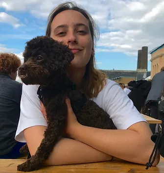 Picture of Toni sitting at a bench cuddling a small dog